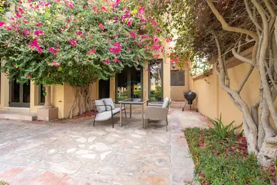 a patio with a table and chairs under a tree at Luxury Beachfront Villa with Direct Beach Access, Next to Community Pool, Close to the Thrills of Aquaventure Waterpark, Canal Cove, Palm Jumeirah by Deluxe Holiday Homes in Dubai
