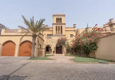 a building with a clock tower and a palm tree at Luxury Beachfront Villa with Direct Beach Access, Next to Community Pool, Close to the Thrills of Aquaventure Waterpark, Canal Cove, Palm Jumeirah by Deluxe Holiday Homes in Dubai