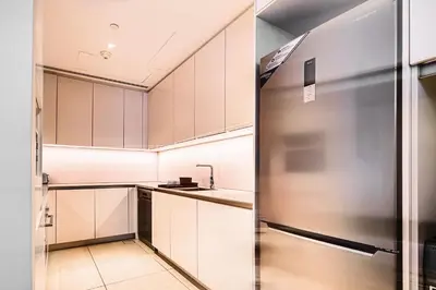 a kitchen with white cabinets and a stainless steel refrigerator at Brand New 5* Luxury Apartment in Address JBR in Dubai