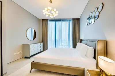 a bedroom with a large white bed and a chandelier at Brand New 5* Luxury Apartment in Address JBR in Dubai