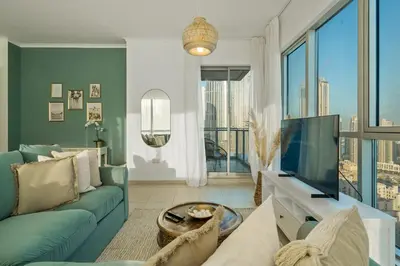 a living room with a blue couch and a tv at Chic and Zen Apartment, Near Burj Khalifa Tower in Dubai