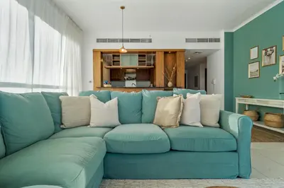 a blue couch with white pillows in a living room at Chic and Zen Apartment, Near Burj Khalifa Tower in Dubai