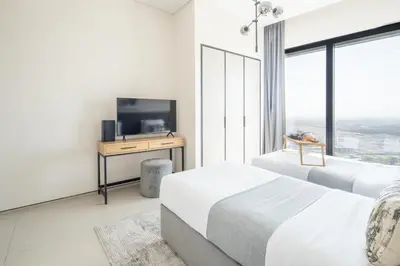a bedroom with two beds and a desk with a television at Frank Porter - The Address JBR in Dubai