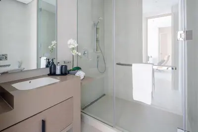 a bathroom with a glass shower and a sink at Frank Porter - The Address JBR in Dubai