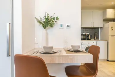 a kitchen with a table with two chairs and a tableasteryasteryasteryasteryastery at Silkhaus studio in DIFC with Burj Khalifa view, pool & gym in Dubai