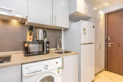 a kitchen with a washer and dryer and a refrigerator at Silkhaus studio in DIFC with Burj Khalifa view, pool & gym in Dubai
