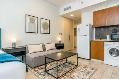 a living room with a couch and a kitchen at Silkhaus newly furnished studio facing DIFC with pool and gym access in Dubai