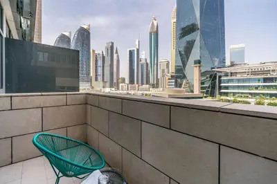 a green chair on a balcony with a city skyline at Silkhaus newly furnished studio facing DIFC with pool and gym access in Dubai