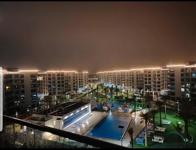 a large apartment building with a swimming pool at night at Peaceful 1BR at MAG 505 Dubai South by Deluxe Holiday Homes in Dubai