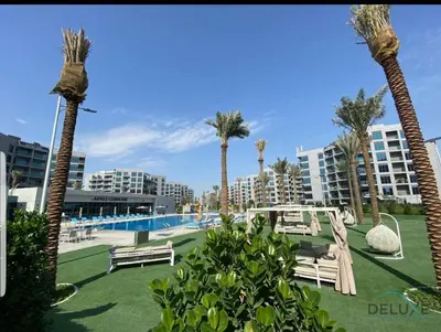 a resort with a pool and palm trees and buildings at Peaceful 1BR at MAG 505 Dubai South by Deluxe Holiday Homes in Dubai