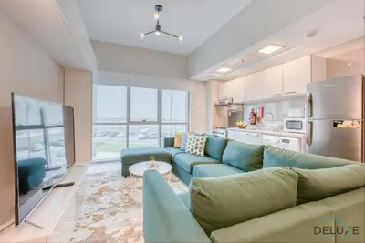 a living room with a blue couch and a kitchen at Peaceful 1BR at MAG 505 Dubai South by Deluxe Holiday Homes in Dubai