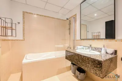 a bathroom with a sink and a tub and a mirror at Elegant 2BR at Bahar 2 JBR by Deluxe Holiday Homes in Dubai