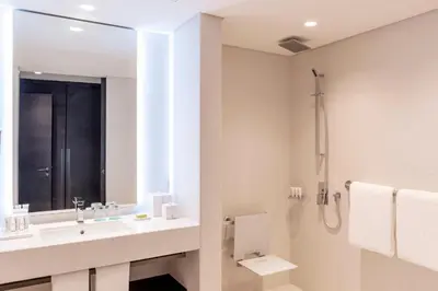 a white bathroom with a sink and a shower at Le Royal Meridien Beach Resort & Spa Dubai in Dubai