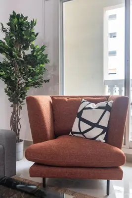 a brown couch with a pillow in a living room at The Smart Concierge - Plaza residences in Dubai