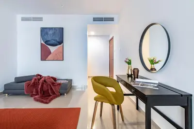 a living room with a desk and a green chair at The Smart Concierge - Plaza residences in Dubai