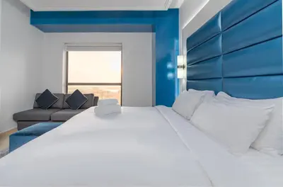 a bedroom with a large white bed with a blue headboard at Elan Rimal 5 Suites in Dubai