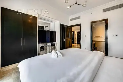 a bedroom with a large white bed and a tv at Fairmont Apartments The Palm, Free access to hotel beach and pools in Dubai