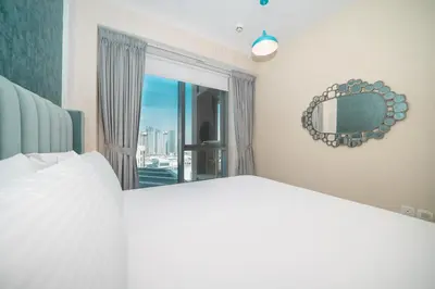 a bedroom with a bed and a mirror and a window at BellaVista - Sophisticated - 2 BR - 29 Boulevard - Burj Khalifa & Fountain View in Dubai
