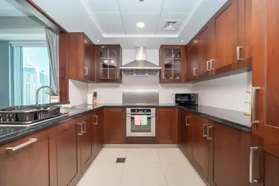 a kitchen with wooden cabinets and a stove top oven at BellaVista - Sophisticated - 2 BR - 29 Boulevard - Burj Khalifa & Fountain View in Dubai