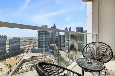 a balcony with two chairs and a view of a city at Unlock Metropolis Business Bay in Dubai