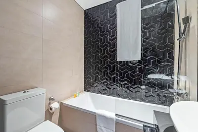 a bathroom with a tub and a toilet and a sink at Unlock Metropolis Business Bay in Dubai