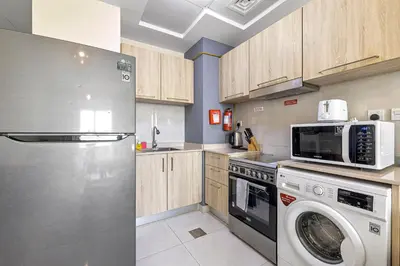 a kitchen with a refrigerator and a washer and dryer at Unlock Metropolis Business Bay in Dubai