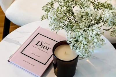 a candle and a book on a table with a vase of flowers at Unlock J One Downtown Dubai in Dubai