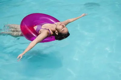 a young girl swimming in a pool with a pink float at Unlock Waters Edge in Dubai
