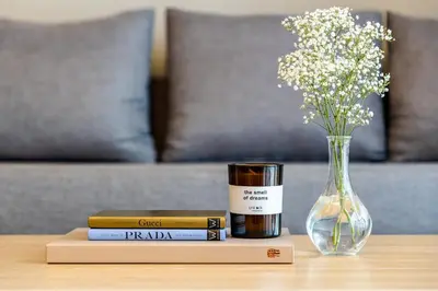 a table with books and a vase of flowers and a candle at Unlock Waters Edge in Dubai