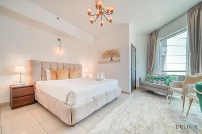 a bedroom with a large bed and a chandelier at Classy 2BR at La Riviera Dubai Marina by Deluxe Holiday Homes in Dubai