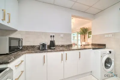a kitchen with white cabinets and a washer and dryer at Classy 2BR at La Riviera Dubai Marina by Deluxe Holiday Homes in Dubai