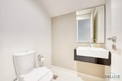 a white bathroom with a toilet and a sink at Extensive 3BR Townhouse at Janusia Damac Hills 2 by Deluxe Holiday Homes in Dubai
