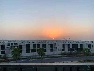 a sunset view from the balcony of a building at Extensive 3BR Townhouse at Janusia Damac Hills 2 by Deluxe Holiday Homes in Dubai
