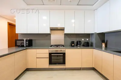 a large kitchen with white cabinets and appliances at Azizi Mina The Palm, Free beach and pool access in Dubai