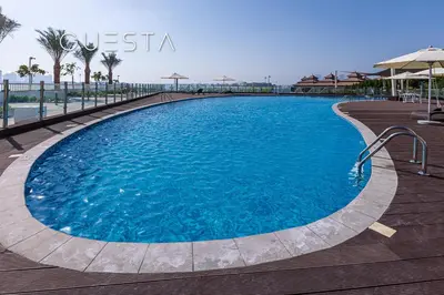 a large blue swimming pool on a wooden deck at Azizi Mina The Palm, Free beach and pool access in Dubai