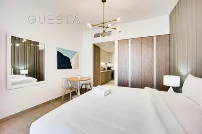 a white bedroom with a large bed and a table at LIV Residence, Dubai Marina in Dubai