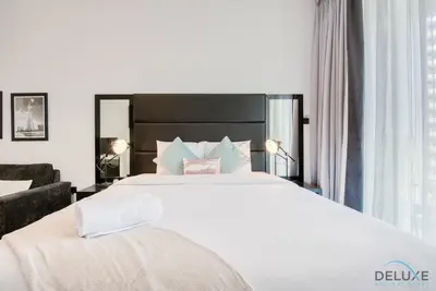 a bedroom with a large white bed and a chair at Radiant Studio at Giovanni Boutique Suites DSC by Deluxe Holiday Homes in Dubai