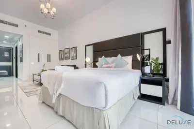 a large white bedroom with a large bed and a mirror at Radiant Studio at Giovanni Boutique Suites DSC by Deluxe Holiday Homes in Dubai