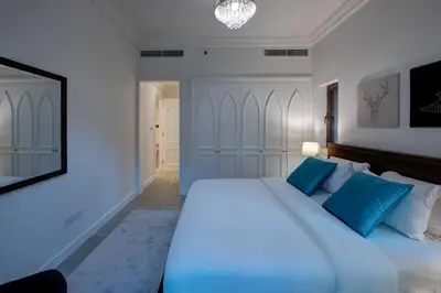 a bedroom with a large white bed with blue pillows at Durrani Homes - Arabian luxury at Souk Al Bahar besides Burj Khalifa & Dubai Mall in Dubai
