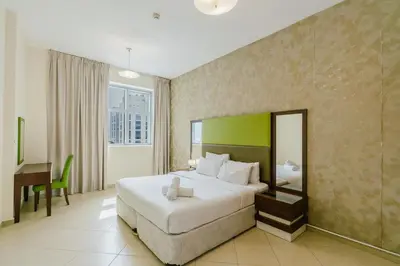 a hotel room with a large bed and a desk at RH- Convenient 1BR, Central, Walk to Mall of Emirates, Al Barsha1 in Dubai