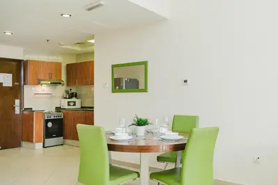 a kitchen with a wooden table and green chairs at RH- Convenient 1BR, Central, Walk to Mall of Emirates, Al Barsha1 in Dubai