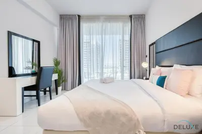 a bedroom with a large white bed and a desk at Captivating Studio at Giovanni Boutique Suites DSC by Deluxe Holiday Homes in Dubai