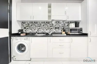 a white kitchen with a washing machine and a microwave at Captivating Studio at Giovanni Boutique Suites DSC by Deluxe Holiday Homes in Dubai
