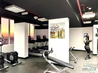 a woman exercising in a gym with cardio machines at Captivating Studio at Giovanni Boutique Suites DSC by Deluxe Holiday Homes in Dubai