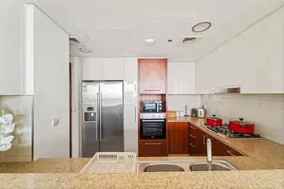 a kitchen with stainless steel appliances and wooden cabinets at Luxury 2BR Skyline Sea View Direct Mall Metro Dining Shops City Walk in Dubai