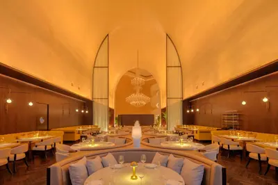 a restaurant with white tables and chairs and a chandelier at The Dubai EDITION in Dubai
