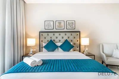 a bedroom with a large bed with blue pillows at Immaculate Studio at DAMAC Celestia by Deluxe Holiday Homes in Dubai