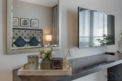 a bathroom with a mirror and a table with flowers at Immaculate Studio at DAMAC Celestia by Deluxe Holiday Homes in Dubai