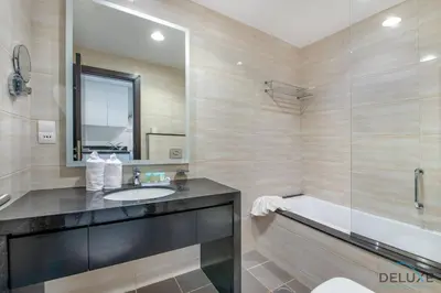 a bathroom with a sink and a tub and a mirror at Immaculate Studio at DAMAC Celestia by Deluxe Holiday Homes in Dubai