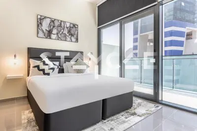 a bedroom with a large white bed and a large window at Staycae Holiday Homes - Merano in Dubai